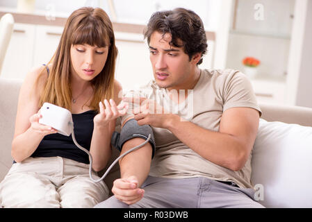 Wife checking husband's blood pressure Stock Photo