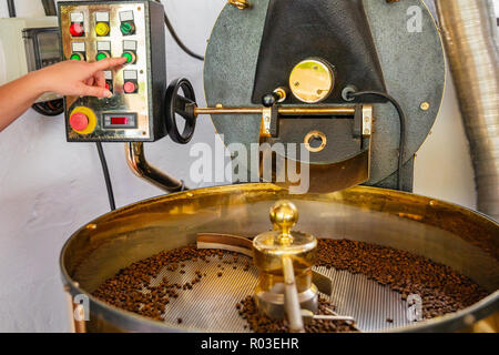 Female Employee Pressing Machinery Button on Coffee Roaster Stock Photo