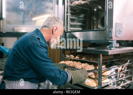 Bearded baker feeling excited before baking nice morning baguettes Stock Photo