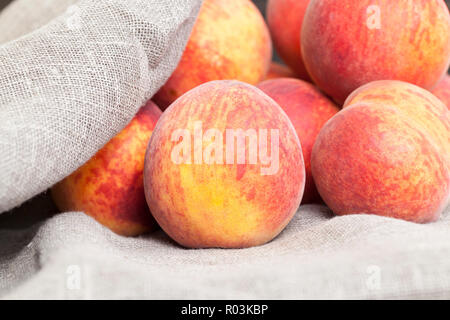 a bunch of ripe large peaches, fruits are in a linen tablecloth Stock Photo