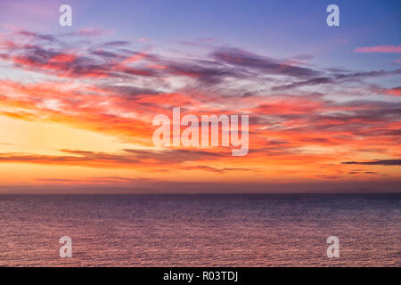 Dramatic sunrise over the sea in vibrant yellow, orange, pink and purple colors. Stock Photo