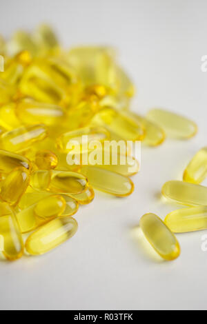 Transparent yellow pills scattered on white background. Fish oil Stock Photo