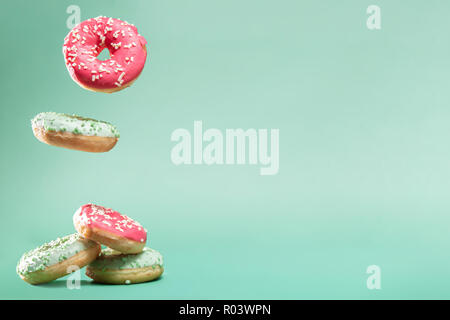Donuts with pink and green icing with sprinkles on mint backround with copyspace for your text Stock Photo