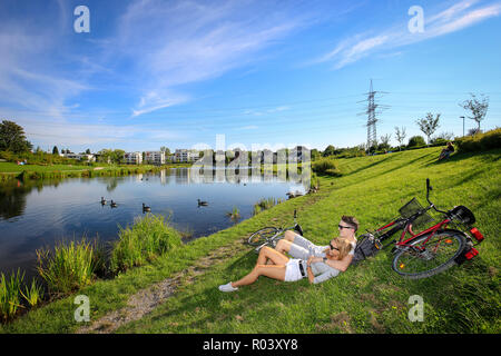 Essen, Ruhr area, Germany, urban development project Niederfeldsee, young couple lies in the meadow Stock Photo