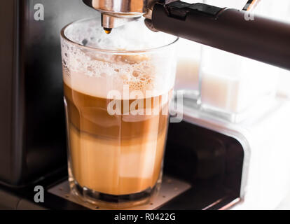 Coffee machine making latte coffee in a transparent glass with milk froth, delicious coffee Stock Photo