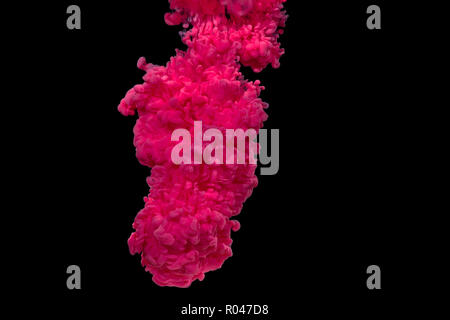 Explosion of red and pink acrylic paint in water on black background. Stock Photo