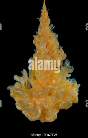 Explosion of golden acrylic paint in water on black background. Stock Photo