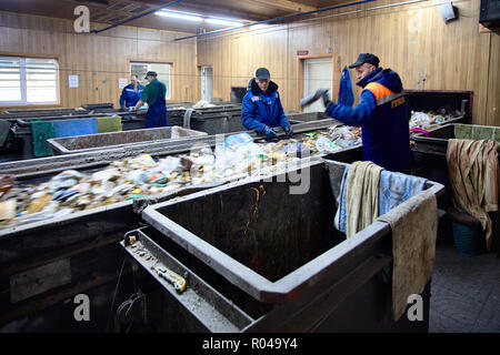 GRODNO, BELARUS - OCTOBER 2018: Four workers in uniform working at waste processing plant sorting recyclable materials from garbage on conveyor belt. Stock Photo
