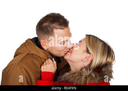 Couple wearing winter clothing - red and brown hooded parka jackets - kissing on isolated background Stock Photo