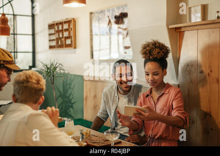 Two smiling friends looking at cellphone photos in a bar  Stock Photo