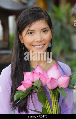 Pretty Asian woman holding lotus flowers bunch Stock Photo
