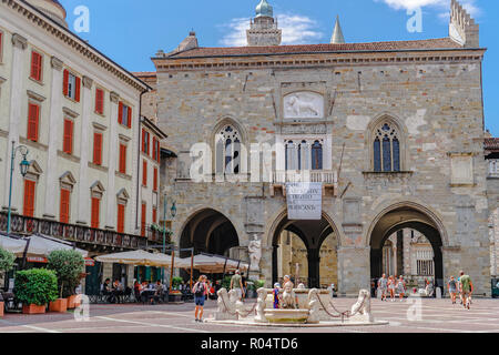 Old Town Palace (Palazzo della Ragione) on Piazza Vecchia with fountain and crowd in Citta Alta, Bergamo, Lombardy, Italy, Europe Stock Photo