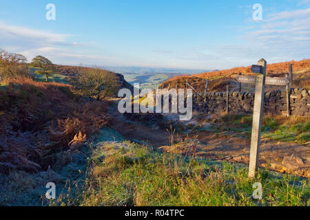 On a clear autumn morning in the Derbyshire Peak District a wooden sign points towards curbar Edge and Baslow Edge. Stock Photo