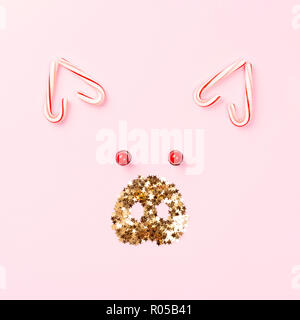 Christmas pig concept made of candy cane lollipops and golden confetti on pink background. Stock Photo