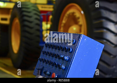 The control panel of the production line in the workshop of the car factory against the background of large black tires Stock Photo