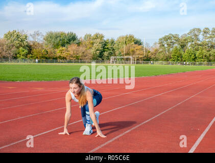 Beautiful woman ready to start running on runway Stock Photo