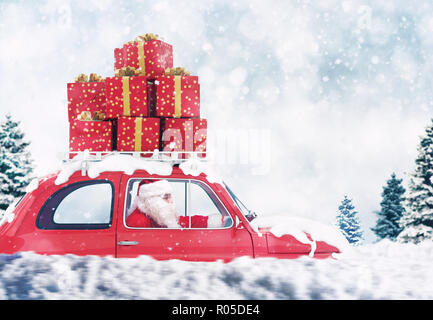 Santa Claus on a red car full of Christmas present with winter background drives to deliver Stock Photo