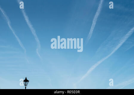 A fragment of a lantern on a blue sky with condensation trails Stock Photo