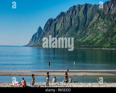 Beach Ersfjordstranden, fjord Ersfjord, public recreation area, summer, people go swimming,  view to mountain range Okshornan,  island Senja, Troms, n Stock Photo