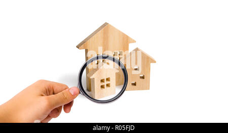 Magnifying glass is looking at the City of wooden houses on a white background. The concept of urban planning, infrastructure projects. Buying and sel Stock Photo