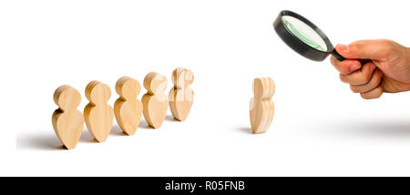 Magnifying glass is looking at the Wooden figures of people stand in the formation and listen to their leader. Business training, briefing and inspira Stock Photo