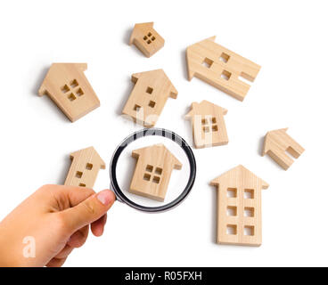 Magnifying glass is looking at the Wooden houses on a white background. The concept of rising prices for housing or rent. growth of the city and its p Stock Photo