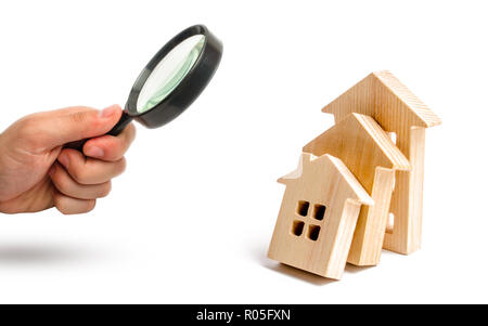 Magnifying glass is looking at the Wooden houses fall on each other like dominoes. concept of falling prices for house purchase and rent. violation of Stock Photo