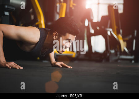 Asian young man doing push-ups at the gym. Muscular female doing pushups. exercise and healthy lifestyle concept. Stock Photo