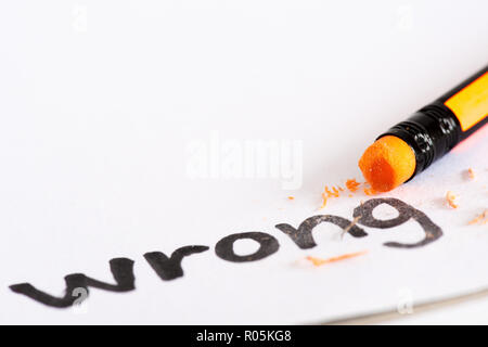 Erase the word Wrong with a rubber concept of eliminating the error, mistake. closeup of a pencil erasing an 'Wrong'. Stock Photo