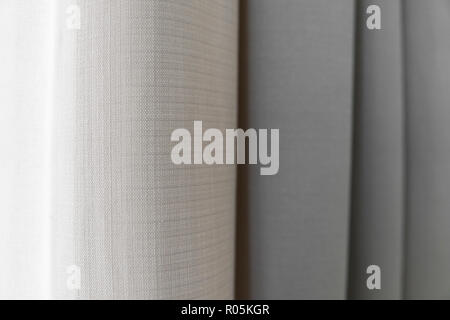 Close-up view of bright curtain in thin and thick vertical folds made of dense fabric.Textured abstract backgrounds and wallpapers.Materials and textiles. Stock Photo