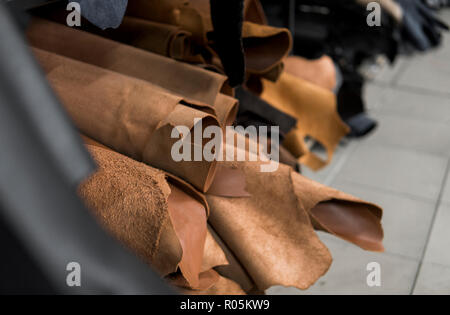 Different pieces of leather in a rolls. The pieces of the colored leathers. Rolls of natural brown red leather. Raw materials for manufacture of bags, shoes, clothing and accessories. Stock Photo