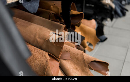 Different pieces of leather in a rolls. The pieces of the colored leathers. Rolls of natural brown red leather. Raw materials for manufacture of bags, shoes, clothing and accessories. Stock Photo