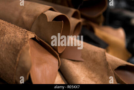 Different pieces of leather in a rolls. The pieces of the colored leathers. Rolls of natural brown red leather. Raw materials for manufacture of bags, shoes, clothing and accessories. Stock Photo