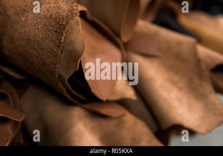 Different pieces of leather in a rolls. The pieces of the colored leathers. Rolls of natural brown red leather. Raw materials for manufacture of bags, shoes, clothing and accessories. Stock Photo