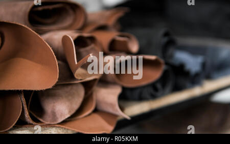 Different pieces of leather in a rolls. The pieces of the colored leathers. Rolls of natural brown red leather. Raw materials for manufacture of bags, shoes, clothing and accessories. Stock Photo