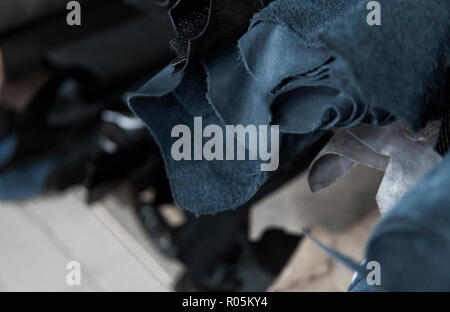 Different pieces of leather in a rolls. The pieces of the colored leathers. Rolls of blue and black leather. Raw materials for manufacture of bags, shoes, clothing and accessories. Stock Photo