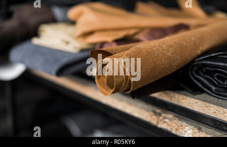 Different pieces of leather in a rolls. The pieces of the colored leathers. Rolls of natural brown red leather. Raw materials for manufacture of bags, shoes, clothing and accessories. Stock Photo