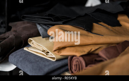 Different pieces of leather in a rolls. The pieces of the colored leathers. Rolls of natural brown red leather. Raw materials for manufacture of bags, shoes, clothing and accessories. Stock Photo