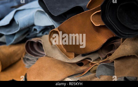 Different pieces of leather in a rolls. The pieces of the colored leathers. Rolls of natural brown red leather. Raw materials for manufacture of bags, shoes, clothing and accessories. Stock Photo