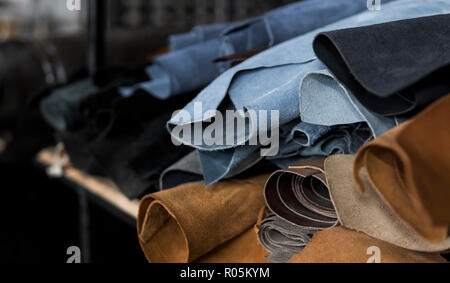 Different pieces of leather in a rolls. The pieces of the colored leathers. Rolls of blue and black leather. Raw materials for manufacture of bags, shoes, clothing and accessories. Stock Photo