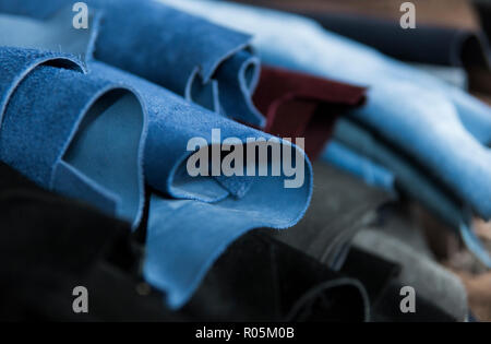 Different pieces of leather in a rolls. The pieces of the colored leathers. Rolls of blue and black leather. Raw materials for manufacture of bags, shoes, clothing and accessories. Stock Photo