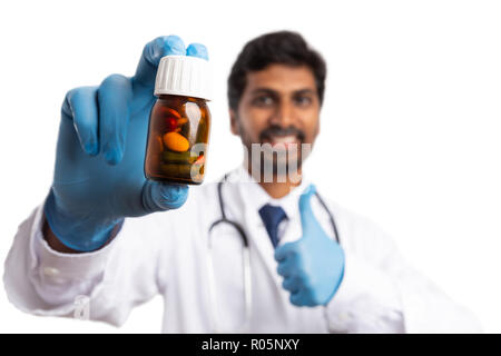 Pills in bottle recommended by smiling indian medic with trustworthy expression holding thumb up as agree gesture isolated on white Stock Photo