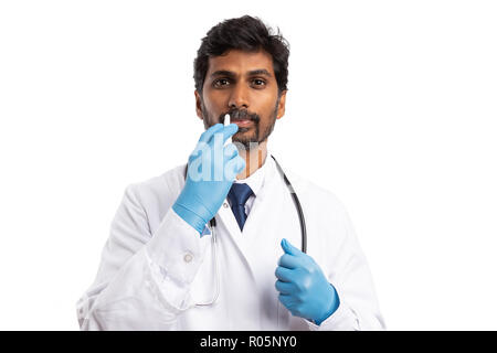 Indian doctor man using nasal spray as flu or allergy concept isolated on white studio background Stock Photo
