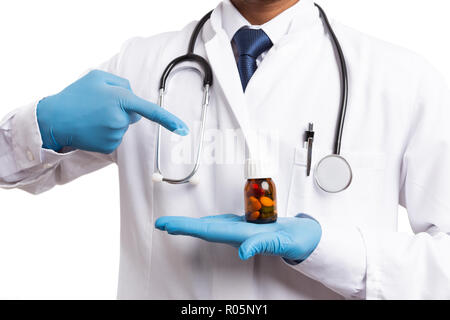 Indian medic wearing blue gloves pointing at pill bottle with index finger isolated on white background Stock Photo