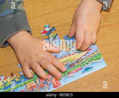 Baby hands assemble the puzzle on the table Stock Photo