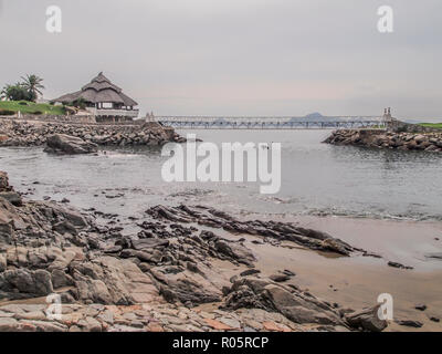 amazing view of a bay with its beach with rocks with a terrace on rocks a bridge with the sea in the background in Manzanillo Colima Mexico Stock Photo