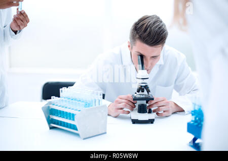 Young scientist looking through a microscope in a laboratory. Young scientist doing some research. Stock Photo