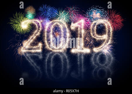 colorful fireworks display and bright sparkler pyrotechnic number 2019 2018 change happy new year sylvester concept on black blue background Stock Photo