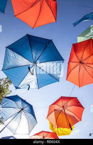 Colored umbrellas on the blue sky background on the street Stock Photo