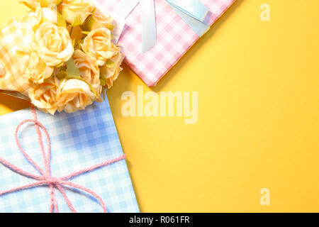 Check pattern colorful gift boxes with flower bouquet on yellow background Stock Photo